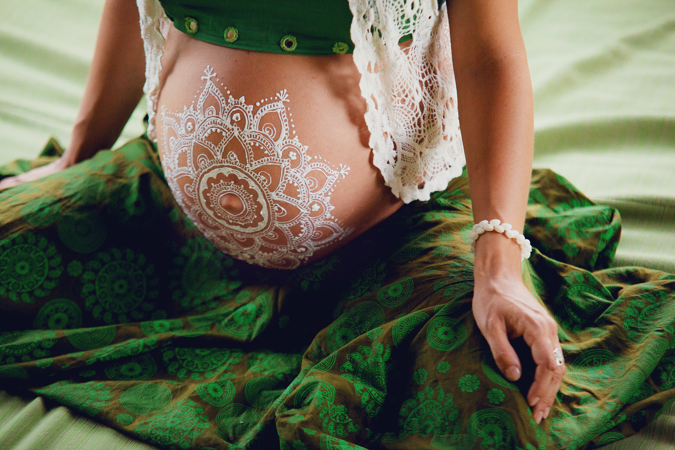 White mehendi on big pregnant belly. Expectation of baby in boho lifestyle.